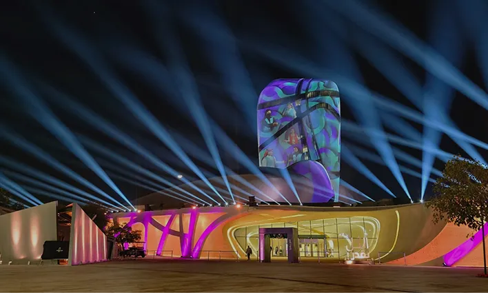 Large production stage with dramatic lighting and presentation screens